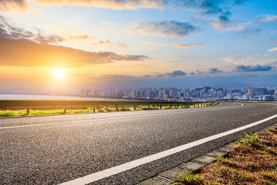海南的柏油路和现代城市天际线，日出的建筑