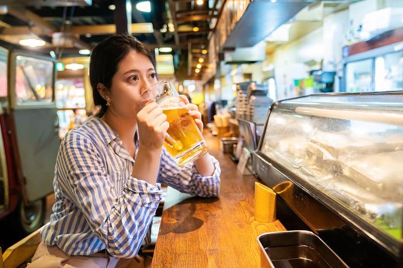 在居酒屋柜台喝酒的亚洲女人。