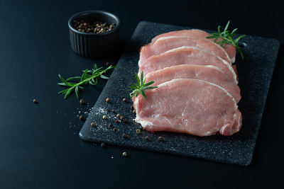 生猪肉片。黑色背景。前视图。空间的文本。