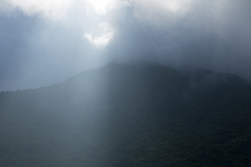 夏日旭日初升的山峦中乌云密布