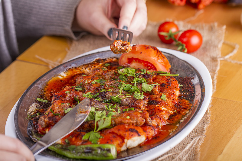 美丽的年轻女子吃土耳其传统Manisa Kebap, Tire Kofte