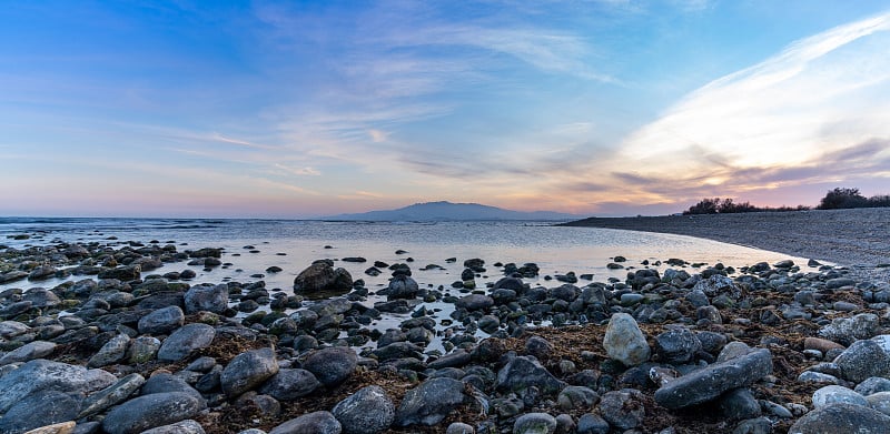 在地中海阿尔梅里亚的一个彩色日落的全景，岩石和潮汐池在前景