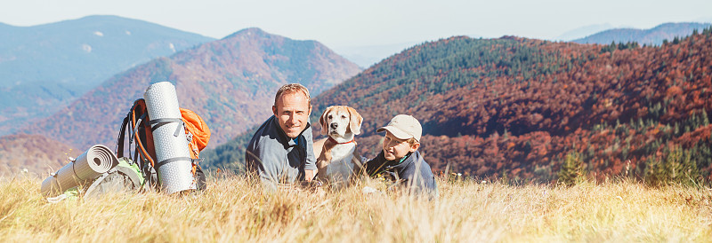 一对父子背包客和他们的小猎犬在山上休息