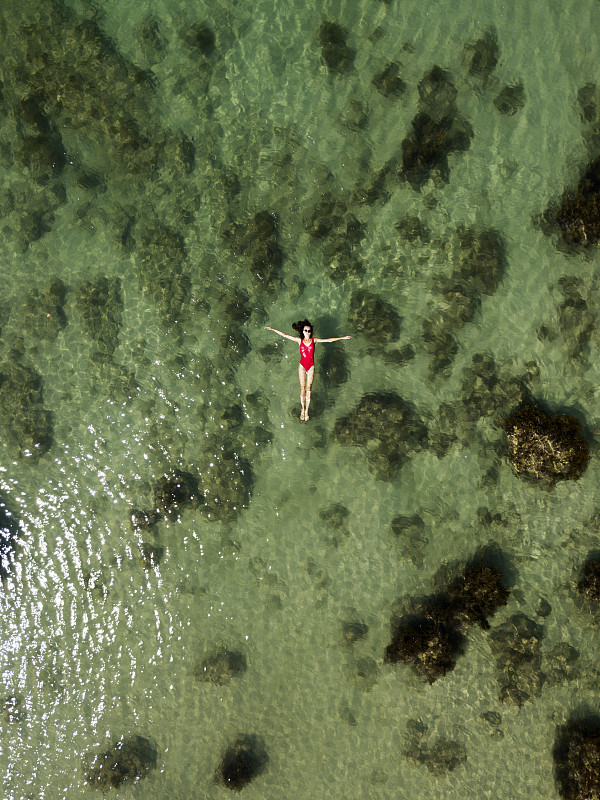 Aerial view of young girl in red swimming suit swi