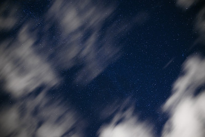 深蓝色夜空的背景，无数闪烁的星星和移动的白云在上面