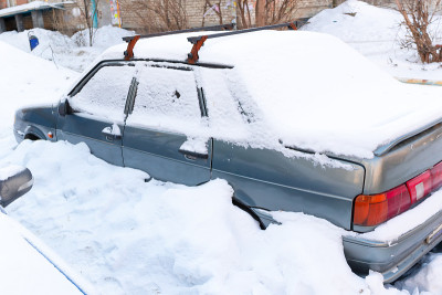 一辆破旧废弃的汽车停在路边，下着一层厚厚的雪