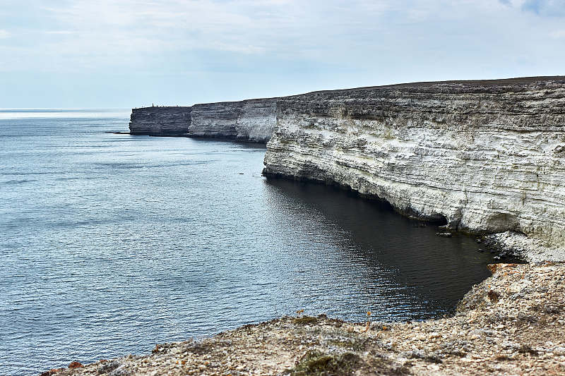 海边的海角。海景，天际线，平静的大海。恶劣的天气，阴云密布，太阳在云后落山。克里米亚，泰克汉库特角，