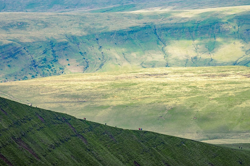 在威尔士布雷肯Beacons的Pan Y Fan附近的山坡上徒步旅行的人们