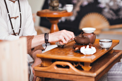 中国茶道是由穿着和服的茶艺大师表演的。男人从茶壶里倒茶特写。