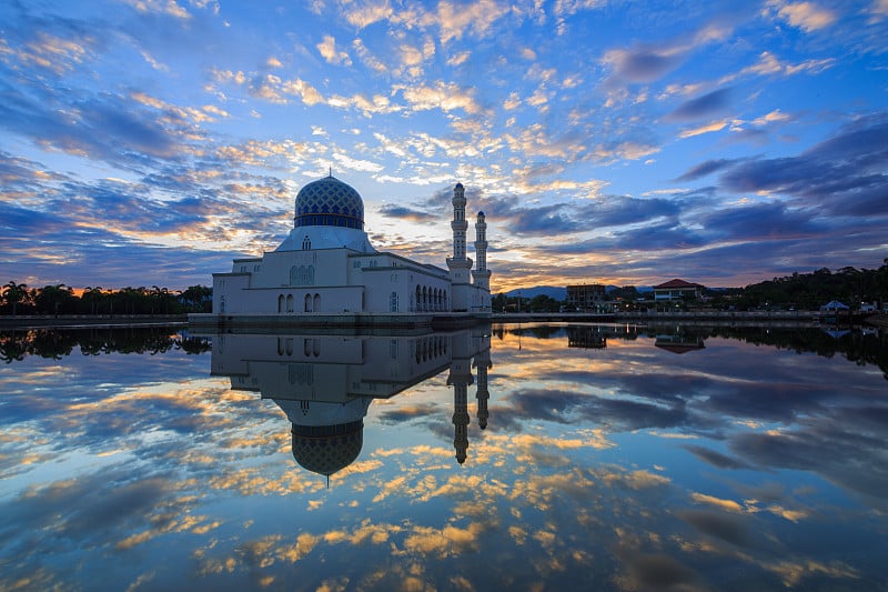 沙巴州的Kota Kinabalu，惊人的日出蓝色时刻，戏剧性的云彩和漂浮清真寺的倒影。