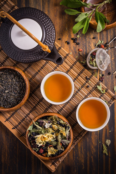 草药和水果茶概念与茶壶和泡茶器和各种草药叶子