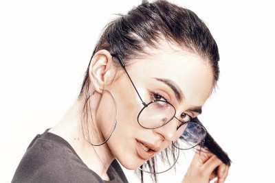 美丽的白人嬉皮士女孩与黑色头发和眼镜是在工作室摆姿势在孤立的背景。