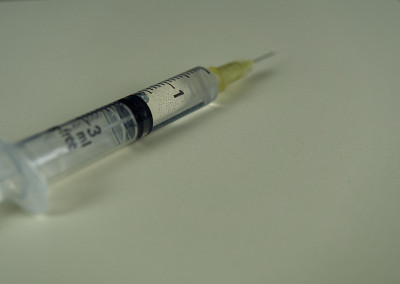 彩色背景上滴有液体的注射器