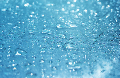 雨滴在蓝色玻璃虚景的背景，闪光的雨滴在玻璃表面，水滴在游泳池的特写