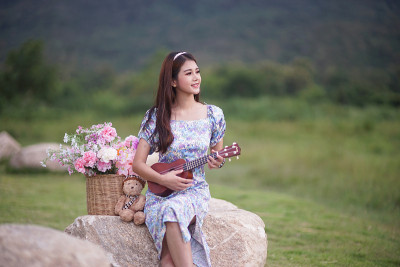 美丽的亚洲女音乐家在自然背景。