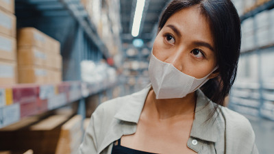 年轻的亚洲女商人经理戴着口罩在零售购物中心用平板电脑检查库存水平。