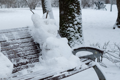 滑稽的雪人坐在公园的长凳上