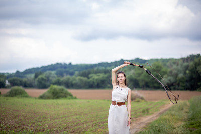 一个匈牙利女人站在草地上，穿着亚麻衣服，拿着鞭子