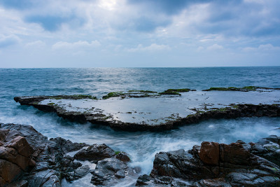 在雨季，海岸上有波浪和青苔的沉积岩海滩