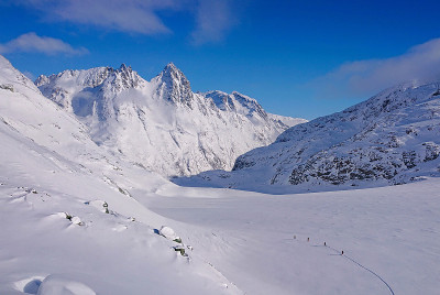 雄伟的积雪覆盖的落基山脉环绕着一群滑雪旅游的游客。