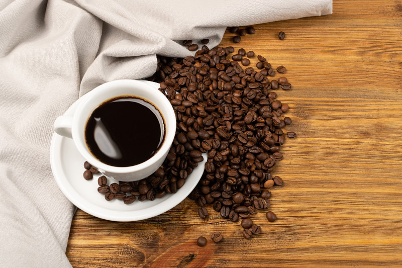 Hot coffee cup and coffee beans on brown backgroun