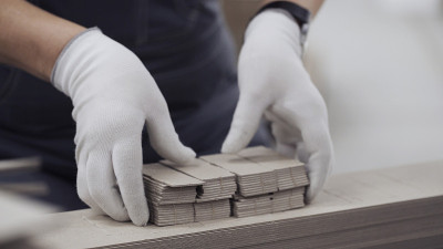 用手套拉近工人的双手，从纸板模具中挤出元素。生产纸箱的现代化工厂。纸板箱用纸制造纸板箱生产包装企业