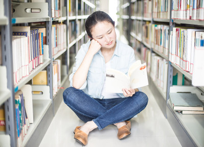 微笑的年轻学生在图书馆看书