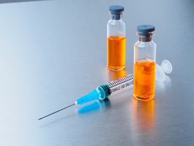 有选择性的重点。注射用注射器和两支冠状病毒疫苗安瓿，背景为银色铝。