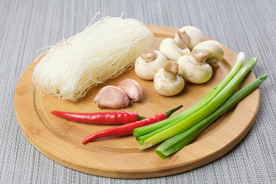 玻璃面条，香槟菜，辣椒豆荚，大葱，大蒜放在砧板上。