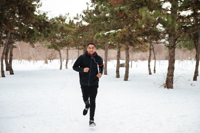 一个活跃的健身者在森林的雪道上慢跑