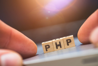 PHP编程网络语言:字母“PHP”的木制立方体躺在笔记本电脑上，概念