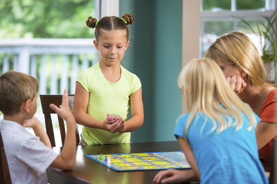 可爱的小女孩和家人玩棋盘游戏
