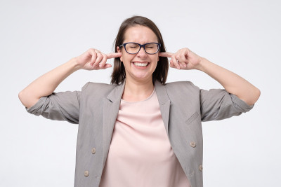 成熟的女人戴着眼镜，有不满的表情，堵着她的耳朵，被噪音惹恼