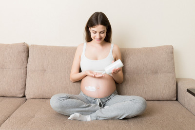 孕妇在腹部涂抹妊娠纹霜。怀孕，人与孕的观念。孕妇在腹部涂抹抗妊娠纹霜