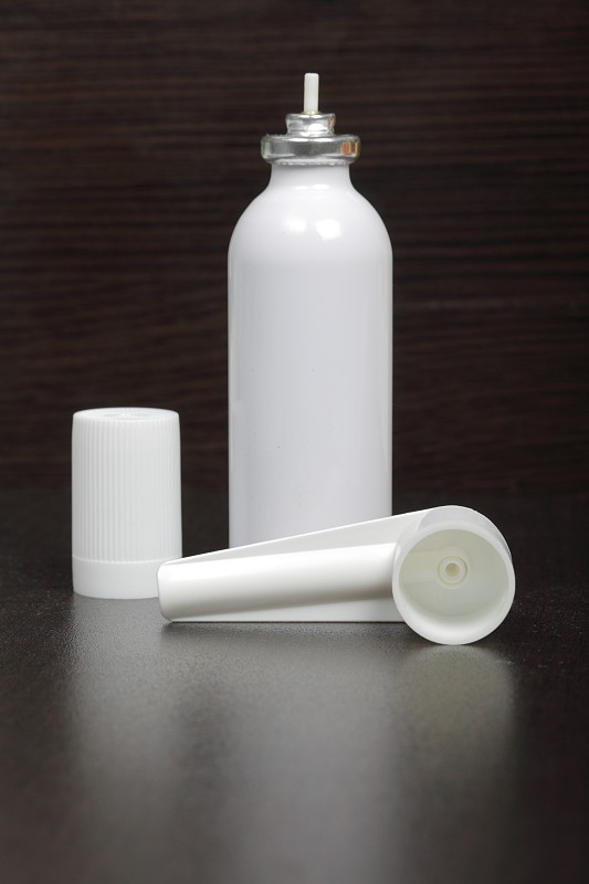 用于治疗呼吸器官的吸入器。喷罐和盖白色。在黑暗的表面。