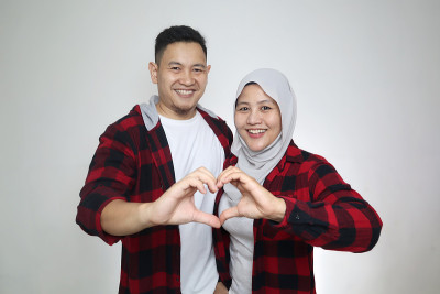肖像快乐的亚洲穆斯林夫妇显示心形的手