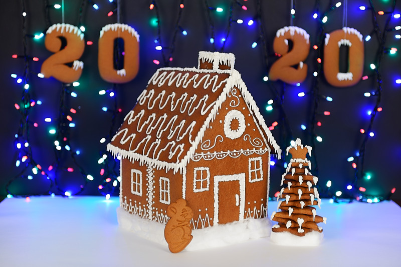手工制作的可食用姜饼屋，2020年的老鼠象征，新年树，2020题词，雪装饰，花环背景照明