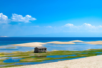 中国青海省青海湖沙岛上的小木屋。沙漠和无尽的清澈的蓝色湖泊