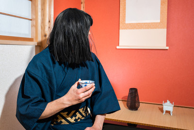 传统的日本人穿着和服和黑头发坐在壁龛挂纸卷轴喝茶仪式