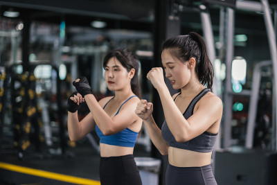 年轻的亚洲女子运动训练拳击手带手腕与教练，拳击练习运动搏击或与伙伴在健身馆锻炼健康的生活方式和自我防
