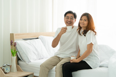 微笑的妻子和丈夫中年喝咖啡卧室。