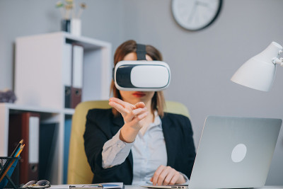 现代商务女性在办公室戴着虚拟现实眼镜。年轻女孩在办公室用VR眼镜。在增强现实领域工作的漂亮女人