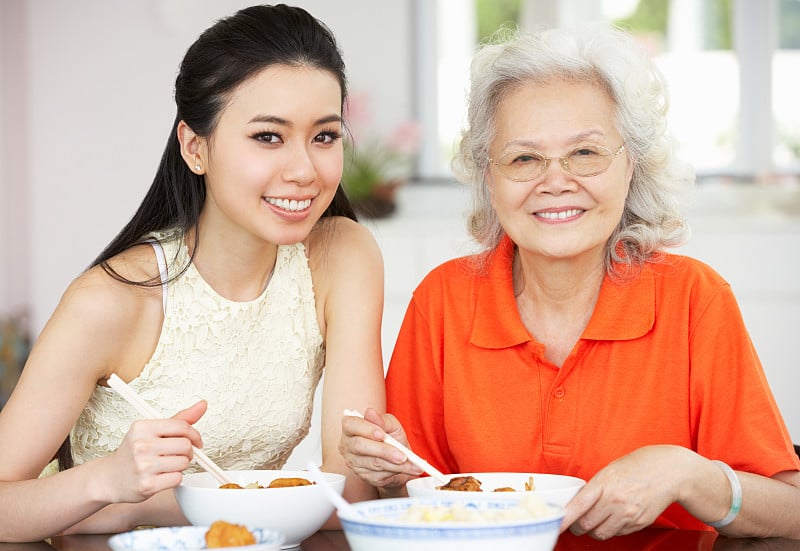 中国母亲和成年女儿在餐桌上吃饭