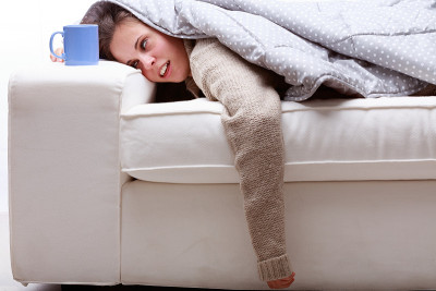 一个裹着羽绒被的年轻女人昏倒在沙发上