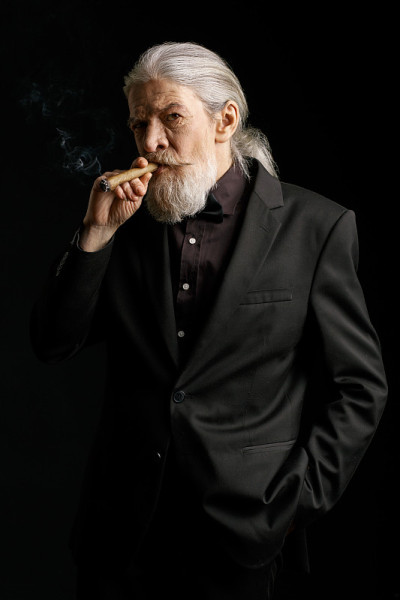满脸皱纹的老人站在黑色背景下