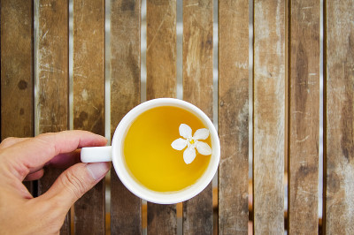 人手一杯茶，木桌上放着白花。