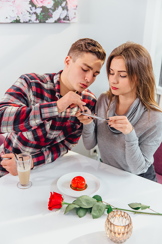 一名女子用智能手机拍甜点照片发到instagram上，她的男友帮助她。