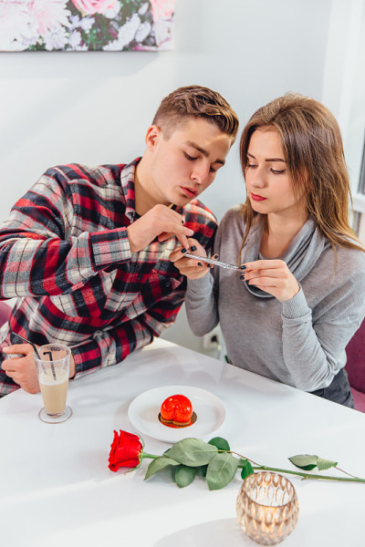 一名女子用智能手机拍甜点照片发到instagram上，她的男友帮助她。