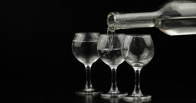 在黑色的背景下，从瓶子中倒出几杯伏特加到玻璃杯中
