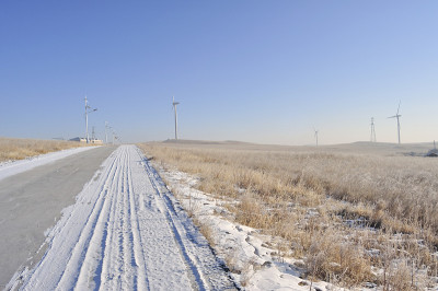 有风力涡轮机和路灯的雪地道路